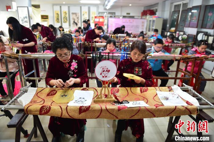 江西省級非遺豫章繡傳承人手把手指導(dǎo)小學(xué)生繡制2022年北京冬奧會吉祥物“冰墩墩”形象。　喻云亮 攝