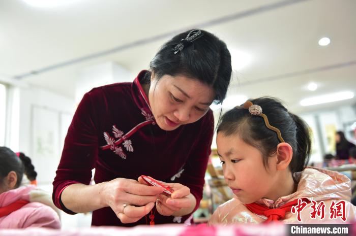 江西省級非遺豫章繡傳承人手把手指導(dǎo)小學(xué)生繡制2022年北京冬奧會吉祥物“冰墩墩”形象。　喻云亮 攝