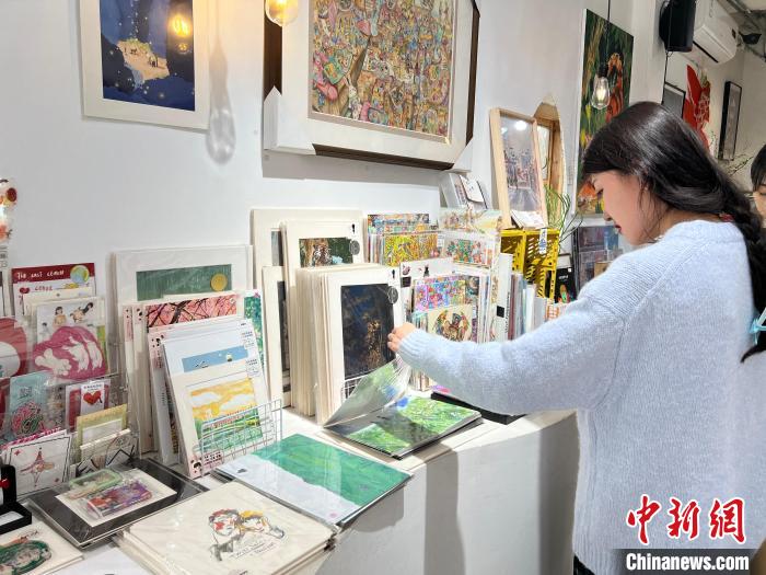 圖為藝術(shù)品商店內(nèi)，顧客挑選插畫作品。　鐘旖 攝