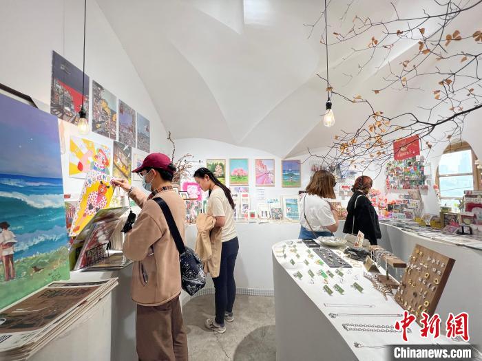 圖為藝術(shù)品商店內(nèi)，顧客挑選插畫作品?！＄婌?攝