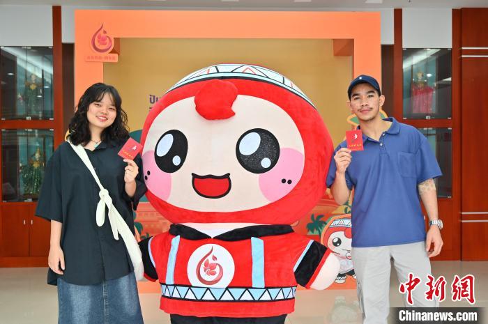 圖為泰國(guó)留學(xué)生手持獻(xiàn)血證與人偶合影。　俞靖 攝