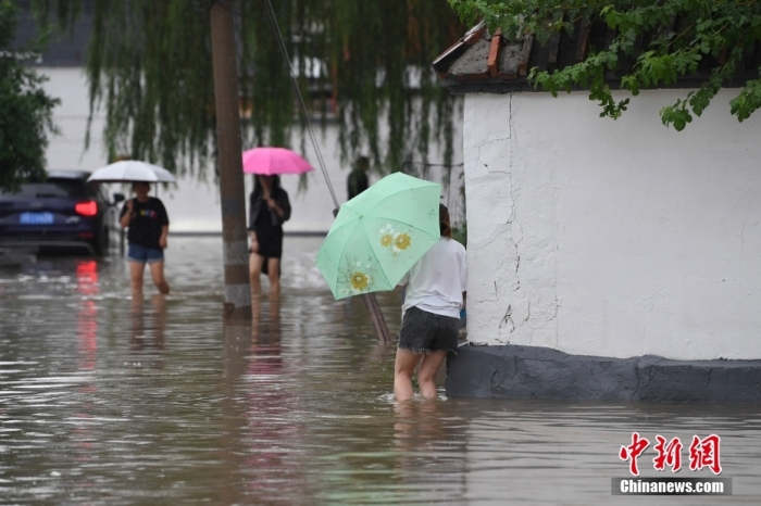 7月31日，市民行走在雨中的北京房山區(qū)瓦窯頭村。北京市氣象臺當日10時發(fā)布分區(qū)域暴雨紅色預警信號。北京市水文總站發(fā)布洪水紅色預警，預計當日12時至14時，房山區(qū)大石河流域將出現(xiàn)紅色預警標準洪水。<a target='_blank' href='/'><p  align=