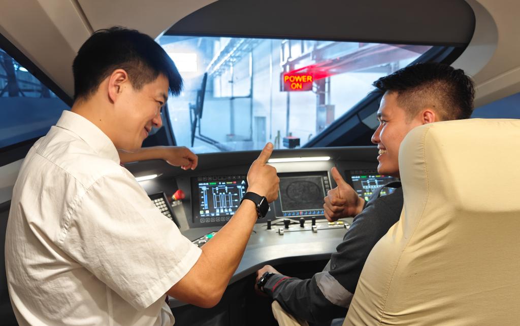 8月25日，在印度尼西亞萬隆的雅萬高鐵德卡魯爾動車所內(nèi)，中國師傅穆振（左）在向印尼火車司機塞蒂亞萬講解動車組出庫前的上電作業(yè)。