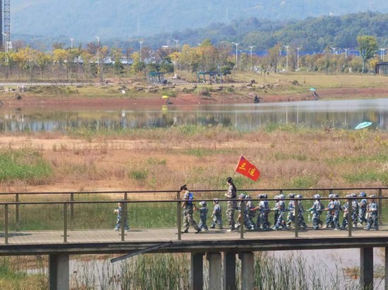 　　10月24日，秋游的幼兒園小朋友在老師帶領下走在清水塘公園里的木橋上。本報記者 常雯宜攝