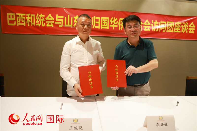 中國(guó)僑聯(lián)副主席、山東省僑聯(lián)主席李興鈺（右）與巴西和統(tǒng)會(huì)會(huì)長(zhǎng)王俊曉簽署合作協(xié)議書(shū)。人民網(wǎng)記者 陳海琪攝
