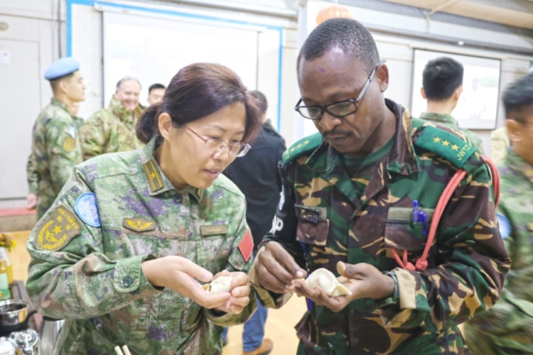 圖為維和官兵與外軍人員共同包餃子。胡光明攝