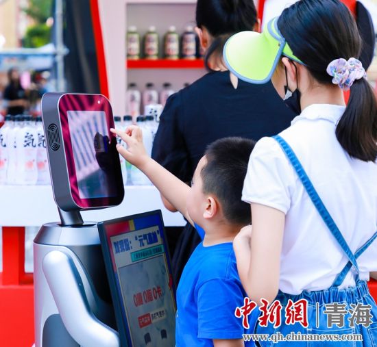 圖為一名小朋友正在和機(jī)器人“志愿者”進(jìn)行互動。 沐聞 攝