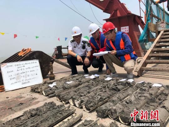 圖為勘察設(shè)計(jì)人員與海事局工作人員查看巖芯情況。　魏震 攝