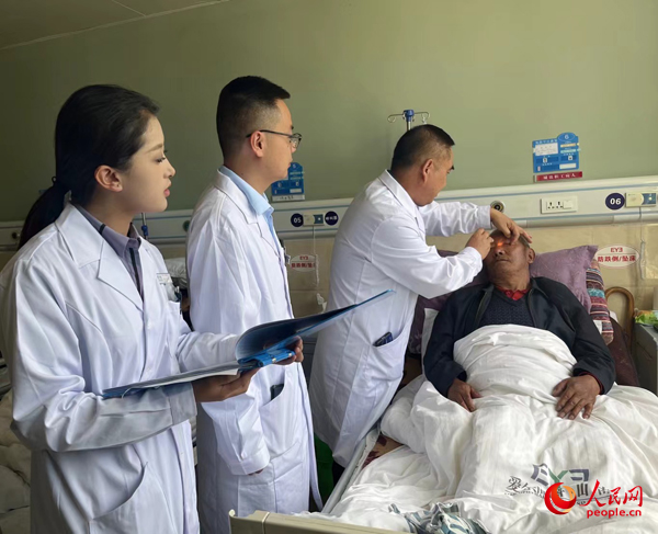 董光明（左三）帶領(lǐng)醫(yī)生對(duì)患者進(jìn)行術(shù)前檢查。人民網(wǎng)記者 杜燕飛攝