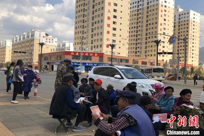 圖為會澤縣城易地扶貧搬遷安置點(diǎn)內(nèi)，老人們聚在廣場上聊天，身后是他們的新家?！】姵?攝