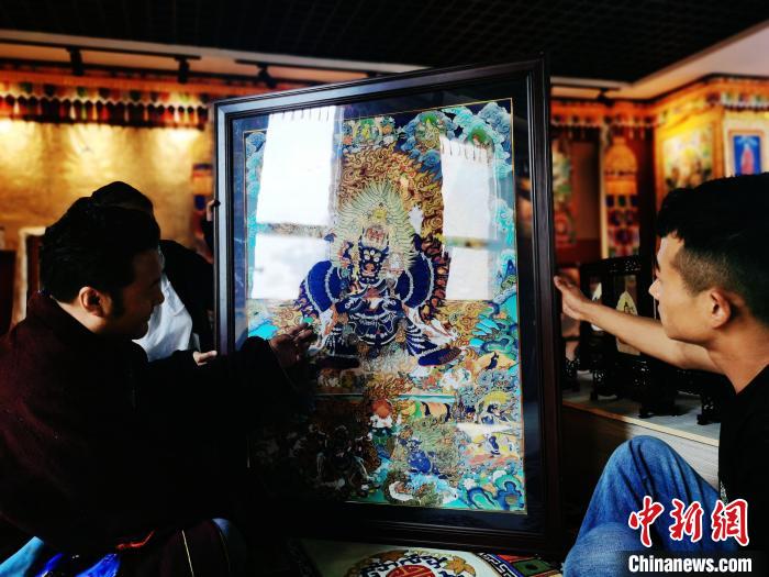 圖為久美尖措(左)與徒弟們展示唐卡作品?！?zhí)砀?攝