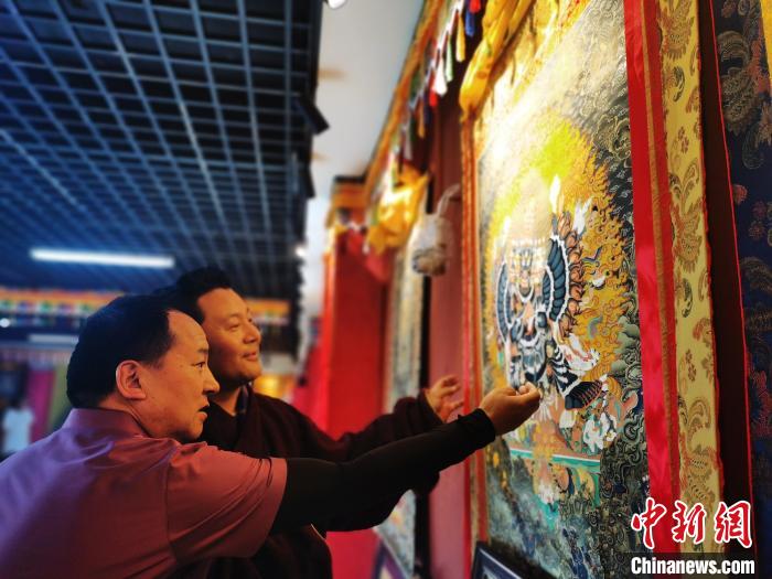圖為久美尖措展示唐卡作品?！?zhí)砀?攝