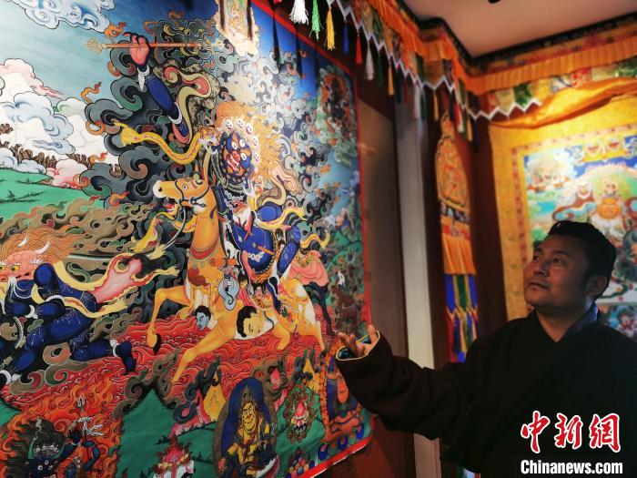 圖為久美尖措展示唐卡作品?！?zhí)砀?攝