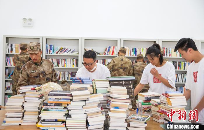 圖為志愿者們和邊防戰(zhàn)士整理圖書?！詵| 攝