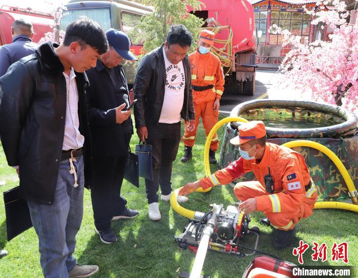 圖為森林消防員為護(hù)林員講解滅火裝備的使用方法?！〔际猩窒乐ш?duì) 供圖