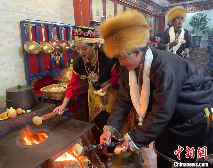 圖為人們在火上烤節(jié)日美食“結(jié)達(dá)”?！∪轿木?攝
