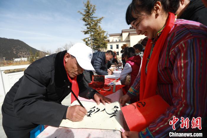 圖為林芝市文聯(lián)書(shū)法家協(xié)會(huì)會(huì)員向民眾贈(zèng)送藏文書(shū)法作品?！埩?攝