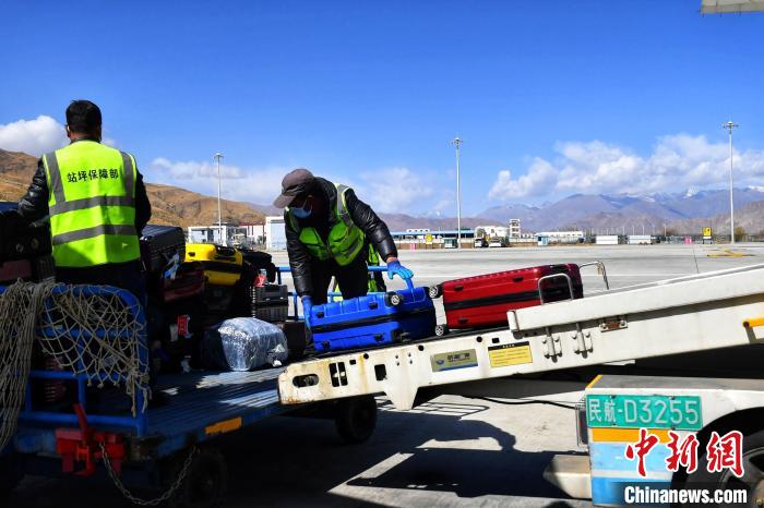 圖為機場工作人員傳送旅客行李箱?！≈芎?攝