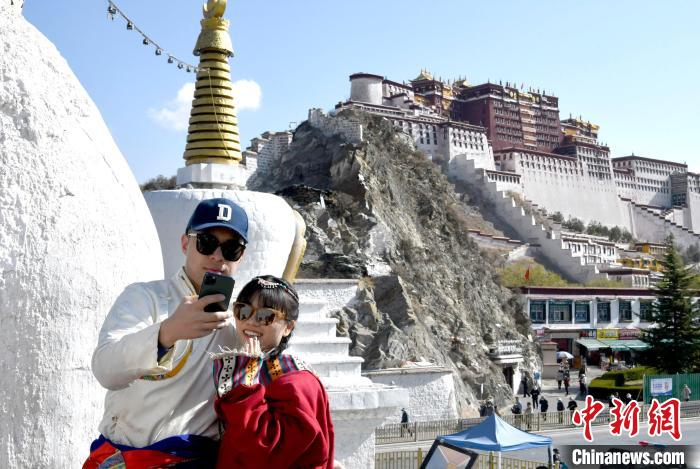 4月17日，游客身著藏式元素服裝在拉薩布達(dá)拉宮觀景臺(tái)拍照留念?！±盍?攝