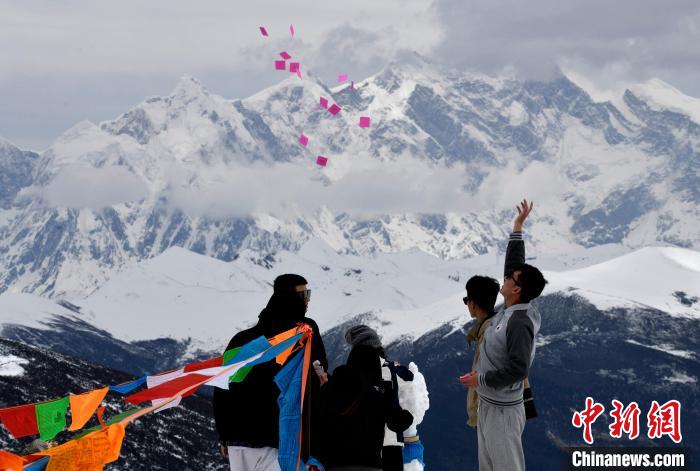 圖為5月14日，游客在西藏林芝色季拉山觀景臺拋灑“隆達”(風馬旗，藏族民眾的一種祈福方式)?！±盍?攝