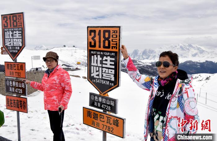 圖為5月14日，西藏林芝色季拉山觀景臺，游客與南迦巴瓦峰合影。　李林 攝
